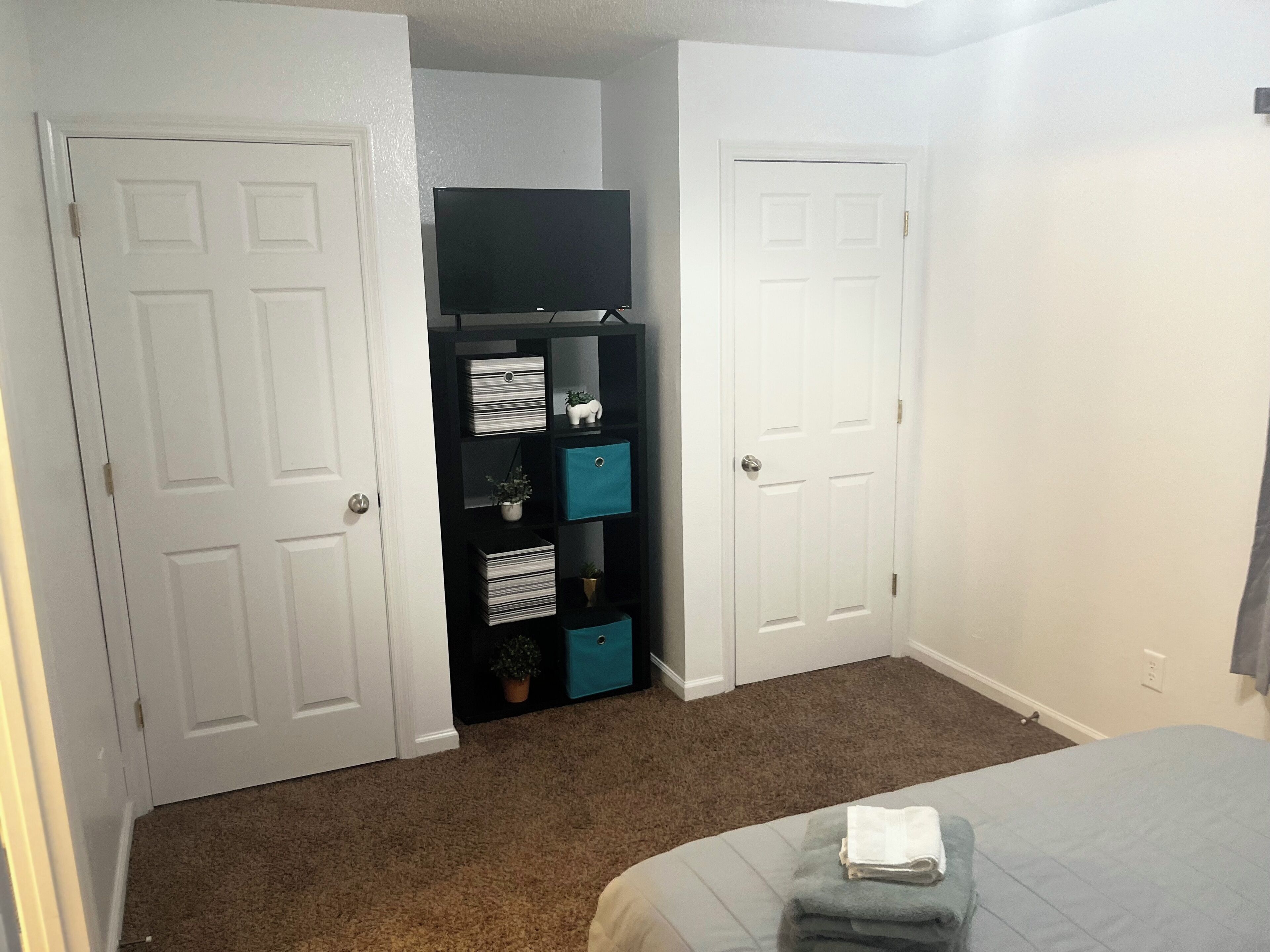 Ein Schlafzimmer mit einem Bett, einem Schrank mit Aufbewahrungsboxen und einer Tür.
