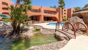 A resort with a pool, palm trees, and a rocky landscape.