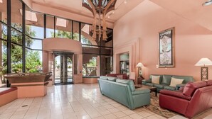 A spacious lobby with a high ceiling, large windows, and a central seating area with sofas.
