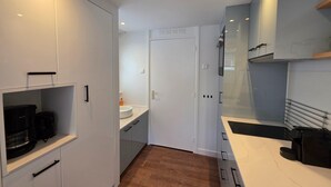 A modern kitchen with white cabinets, a wooden countertop, and a built-in oven. - Charming and Cozy Furnished 2-person Studio Apartment (De Koog)
