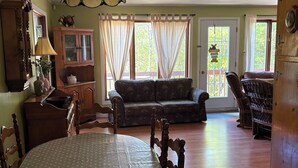 A dining area with a table, chairs, a sofa, and a wooden cabinet. - Chalet Bromont ski in/ski out (Bromont)