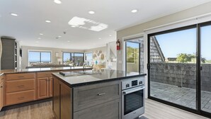 Una cocina moderna con una isla grande, armarios de madera y vistas al exterior a través de un ventanal corredero.