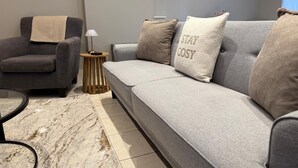 A modern living room with a grey sofa, a grey armchair, and a small round table with a lamp. - School Path in the heart of the historic Ironbridge (Telford)