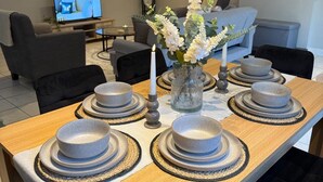 A dining area with a long wooden table set for six, featuring grey plates and bowls, a vase with white flowers, and a lit candle. - School Path in the heart of the historic Ironbridge (Telford)