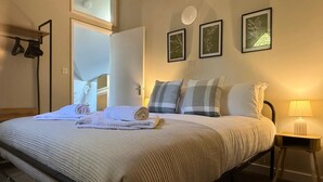 A neatly made bed with a white comforter and pillows, a bedside lamp, and three framed wall art pieces. - School Path in the heart of the historic Ironbridge (Telford)