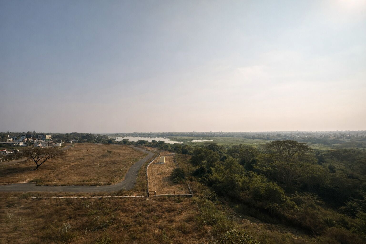 A wide, open landscape with a road curving through a dry, grassy area.