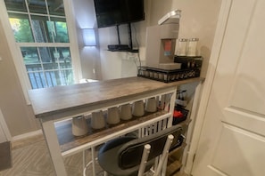 A kitchen with a wooden countertop, a coffee machine, and a TV mounted on the wall. - Tiny Home with 2BR and 2 baths (Oakland)