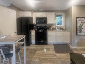A kitchen with white cabinets, a black refrigerator, a microwave, and a stove.