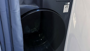 A compact, modern washing machine with a digital display and a 20-year warranty sticker.