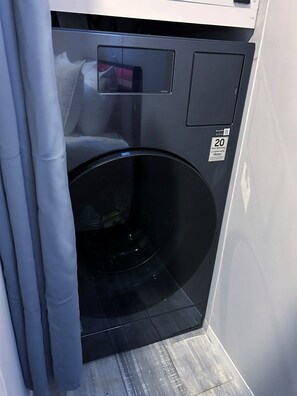 A compact, modern washing machine with a digital display and a 20-year warranty sticker.
