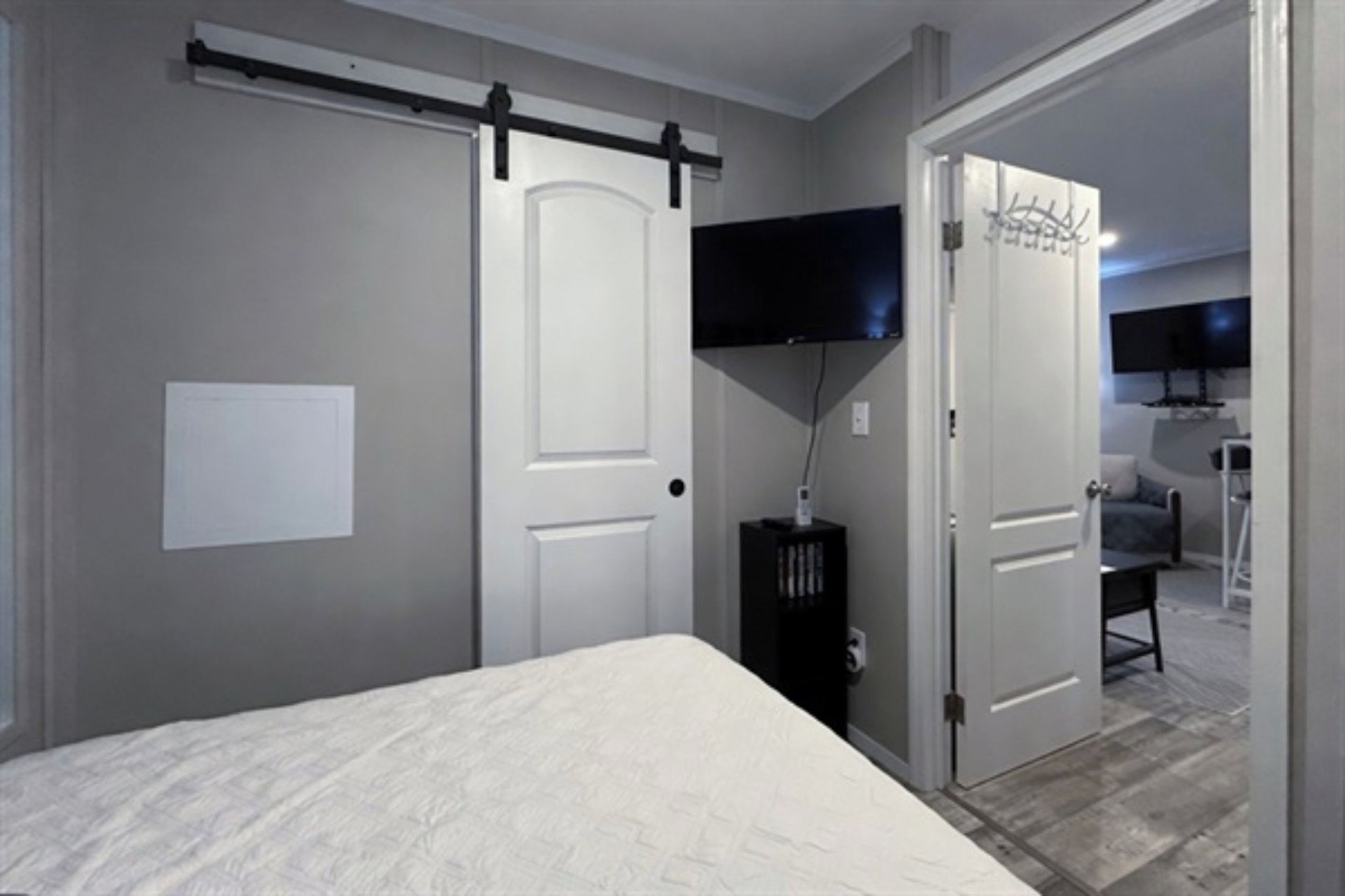 A bedroom with a bed, a sliding door, a television, and a desk.