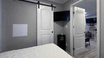 A bedroom with a bed, a sliding door, a television, and a desk.