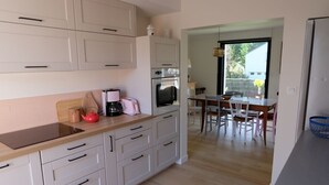 A modern kitchen with white cabinets, a wooden countertop, and a dining area with a table and chairs.