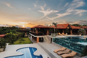 A luxurious resort with a large swimming pool, a covered outdoor area with lounge chairs, and a view of the sunset. - Hotel Antara Resort (Alcalá)