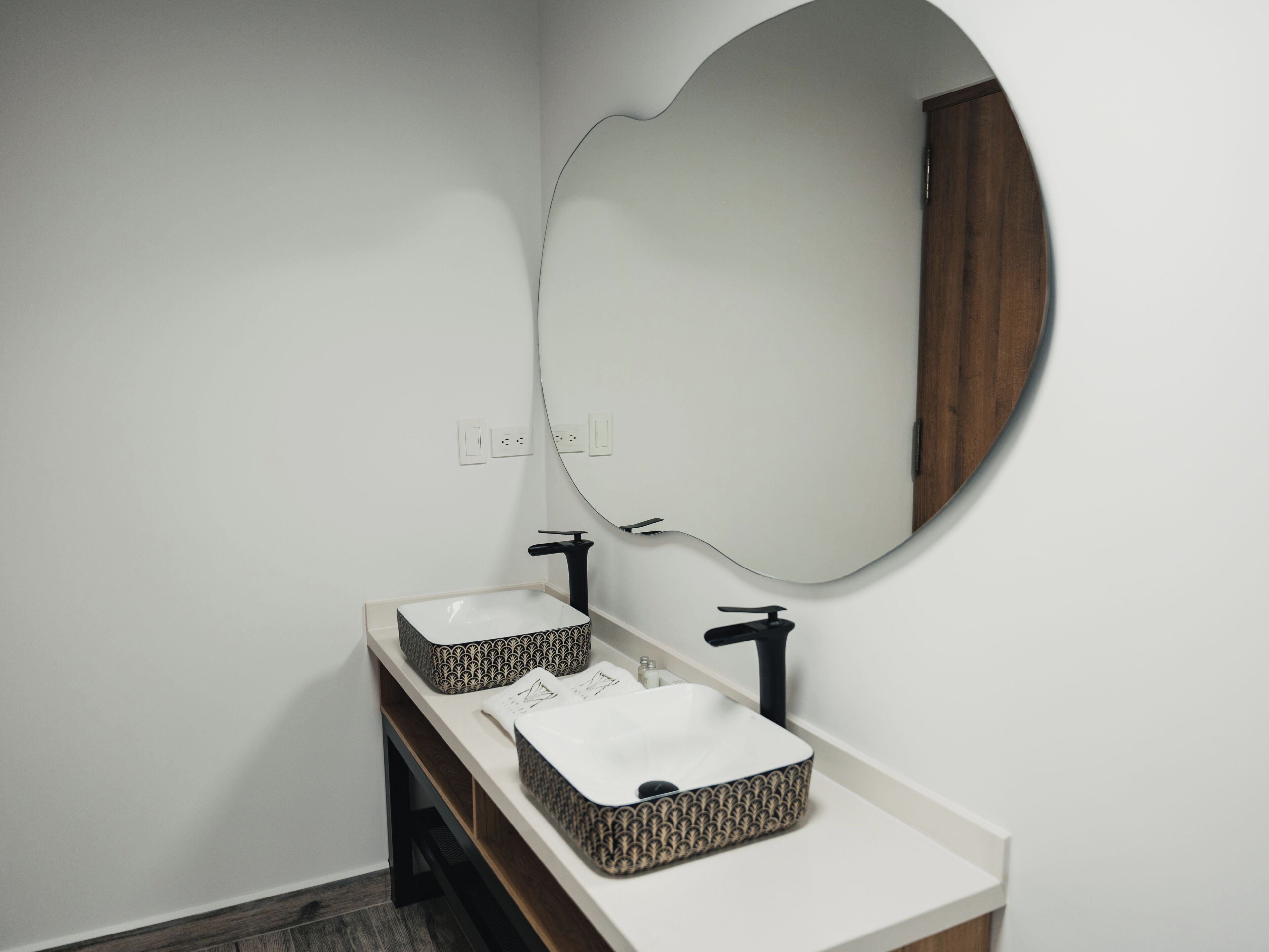 A bathroom with two sinks, a large mirror, and a wooden cabinet.