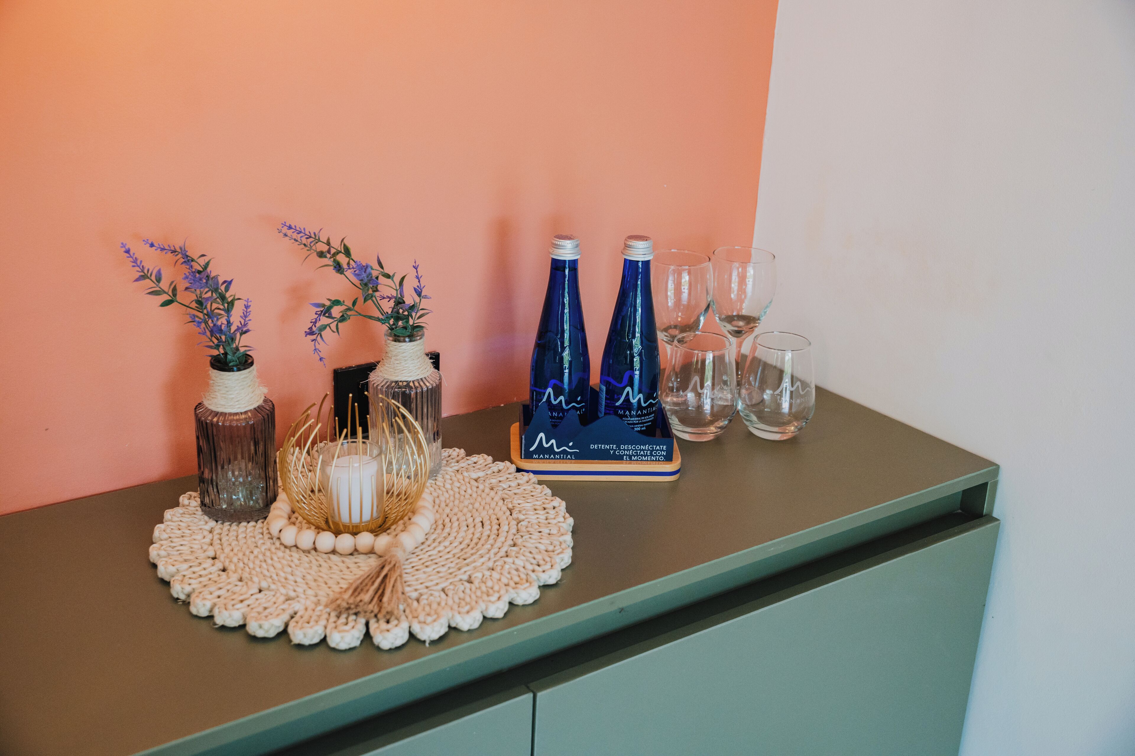 A table with decorative items including vases, a woven placemat, and wine bottles.