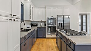Una cocina moderna con armarios blancos, electrodomésticos de acero inoxidable y suelo de madera.