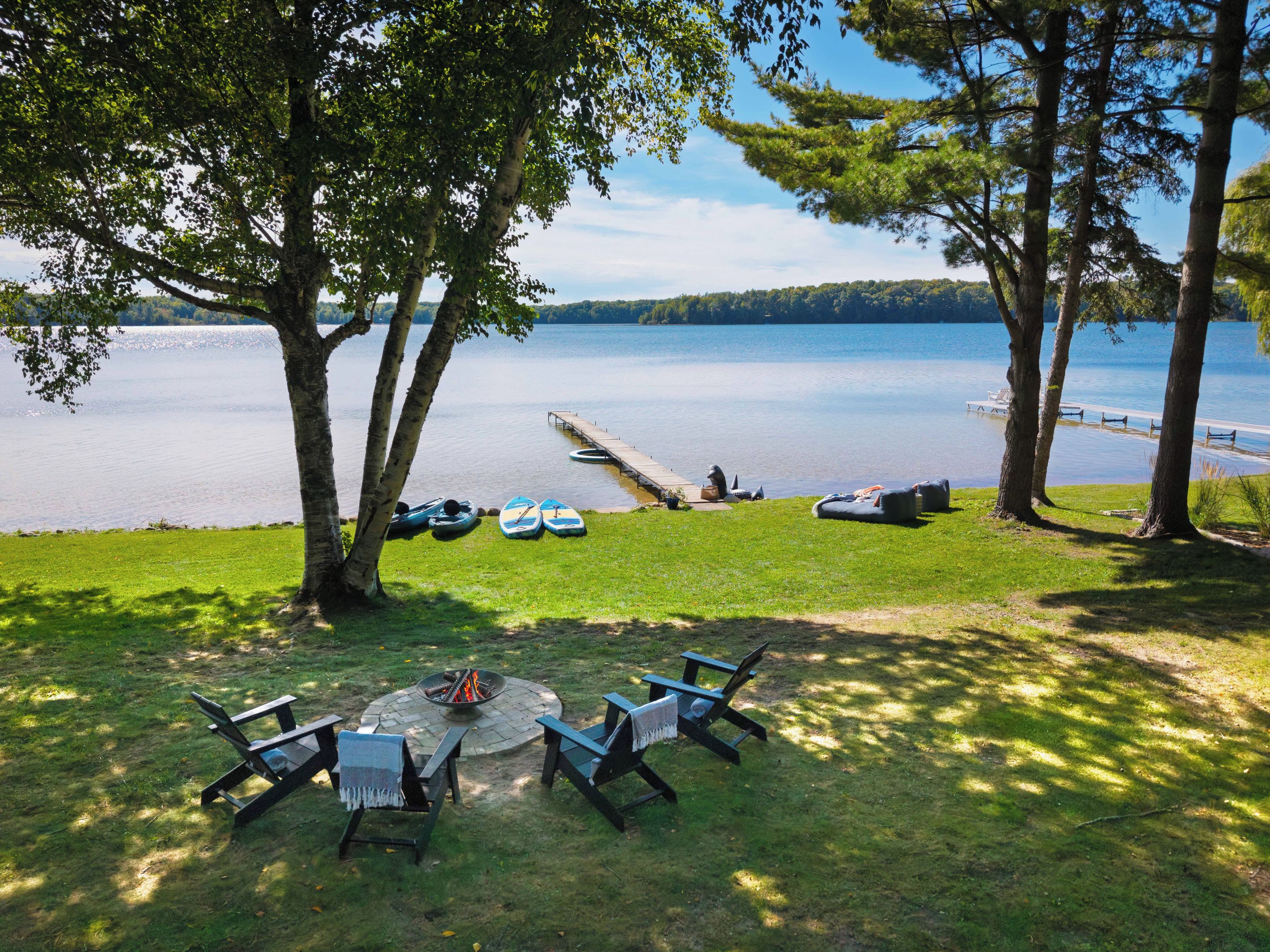 Un espace extérieur aménagé au bord du lac, avec un foyer et des fauteuils confortables.
