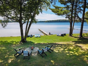 A lakeside outdoor seating area with a fire pit and lounge chairs. - Family + Pet Friendly Holiday Retreat on Lake Ann (Lake Ann)