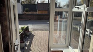 Une véranda donnant sur une allée pavée et un mur de briques.