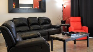 A living room with a black leather sofa, a red armchair, and a coffee table. - Dog Friendly:  Pleasant 4-bedroom pool and spa house near Disney with pool table (Kissimmee)