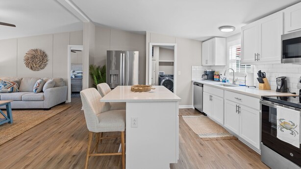 A modern kitchen with white cabinets, stainless steel appliances, and a central island. - Coastal 3BR w/Game Room, 5 mins to beach, FirePit (Shallotte)
