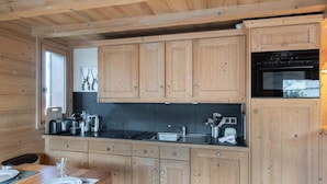 Cocina de estilo cabaña de madera con cubierta negra, armarios de madera y un ventanal.