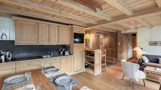 Una cocina amplia con armarios de madera, un comedor con mesa dispuesta para cuatro personas y un rincón de estar acogedor con sofá y sillones.