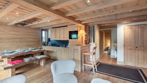 Interior de una cabaña de madera con cocina, comedor y zona de estar.