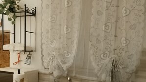 A kitchen with a sink, a microwave, a vase with flowers, and a curtain with a heart pattern. - Three-bed vacation home in the city of the Leaning Tower (Pisa)