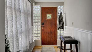 Un couloir avec une porte en bois, un banc et un porte-manteau.