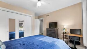 A bedroom with a bed, a desk, a chair, a television, and a wardrobe. - Spacious 3 Bedroom (Cary)
