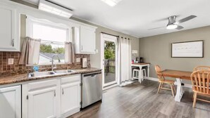 A kitchen with white cabinets, a dishwasher, and a window with curtains. - Spacious 3 Bedroom (Cary)