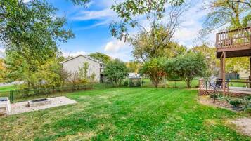 A backyard with a lawn, a wooden deck, and a house.