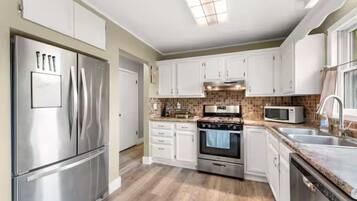 A modern kitchen with white cabinets, stainless steel appliances, and a tiled backsplash.