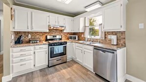 A kitchen with white cabinets, a microwave, stove, oven, and dishwasher. - Spacious 3 Bedroom (Cary)