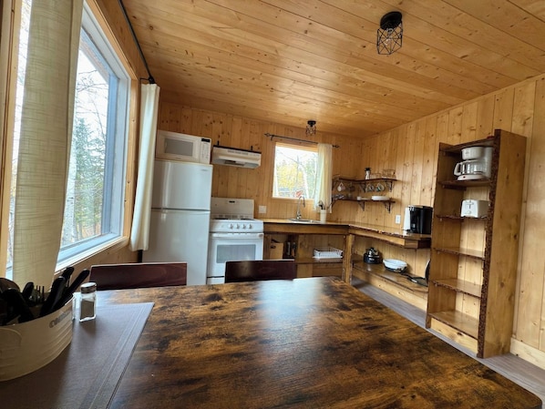 A wooden interior with a kitchen area including a stove, microwave, and sink.