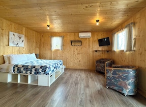Habitació amb panells de fusta, un llit, una televisió i una petita zona de seients.