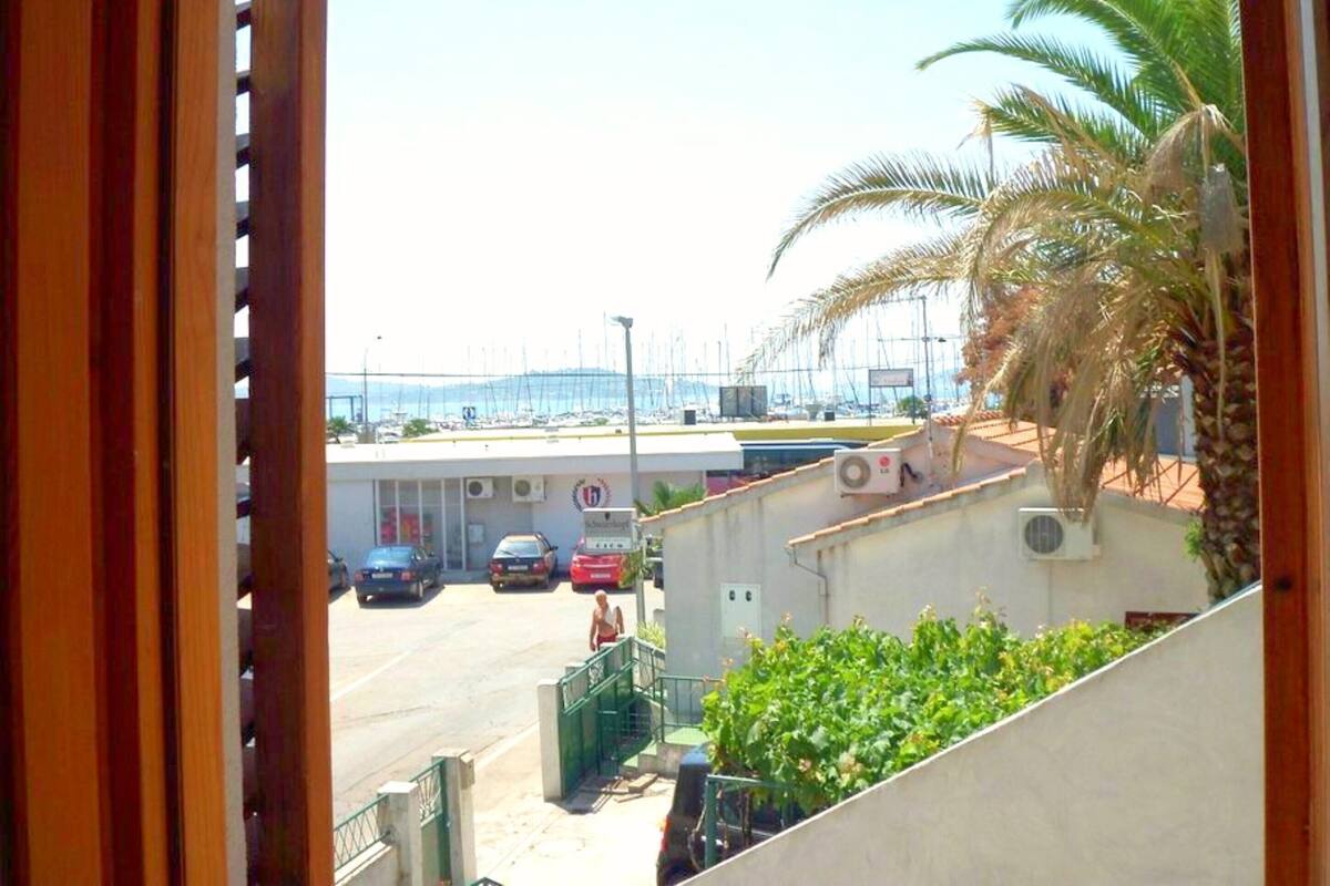 A view from a window overlooking a marina with parked cars and a building with a sign.
