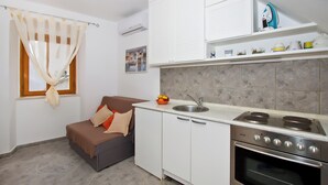 A compact kitchen with white cabinets, a built-in oven, and a countertop with a sink. - Apartment Center Marija best location (Vodice)
