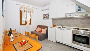 A compact kitchen with a dining table, a sofa, and a built-in oven. - Apartment Center Marija best location (Vodice)