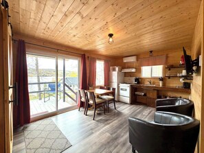 Ein Holzblockhaus mit Essbereich, Küche und einer Schiebeglastür nach draußen.