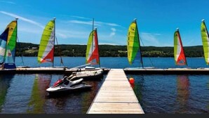 A dock with several sailboats, a jet ski, and a wooden pier extending into a calm body of water. - Mini-chalet#7- Un pur ressourcement - Pohénégamook (Pohenegamook)