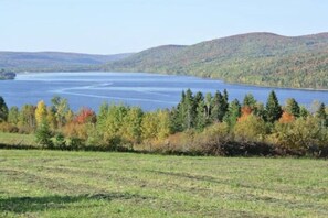 Ein See, umgeben von Hügeln und herbstlich gefärbten Bäumen.
