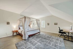 Quarto com uma cama de dossel, uma escrivaninha e uma cadeira.