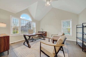 A spacious room with a sloped ceiling, large windows with blinds, a desk with a chair, a sofa, and a bookshelf. - Kid-Friendly Near UD, 1st-Floor Master + Office (Newark)