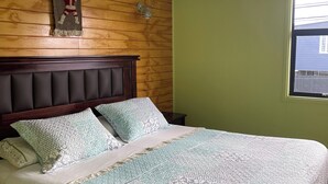 A neatly made bed with patterned bedding, a wooden headboard, and a wall-mounted light fixture. - Casa lucy bed and breakfast. Familiar, comfortable, near to Natales center. (Puerto Natales)