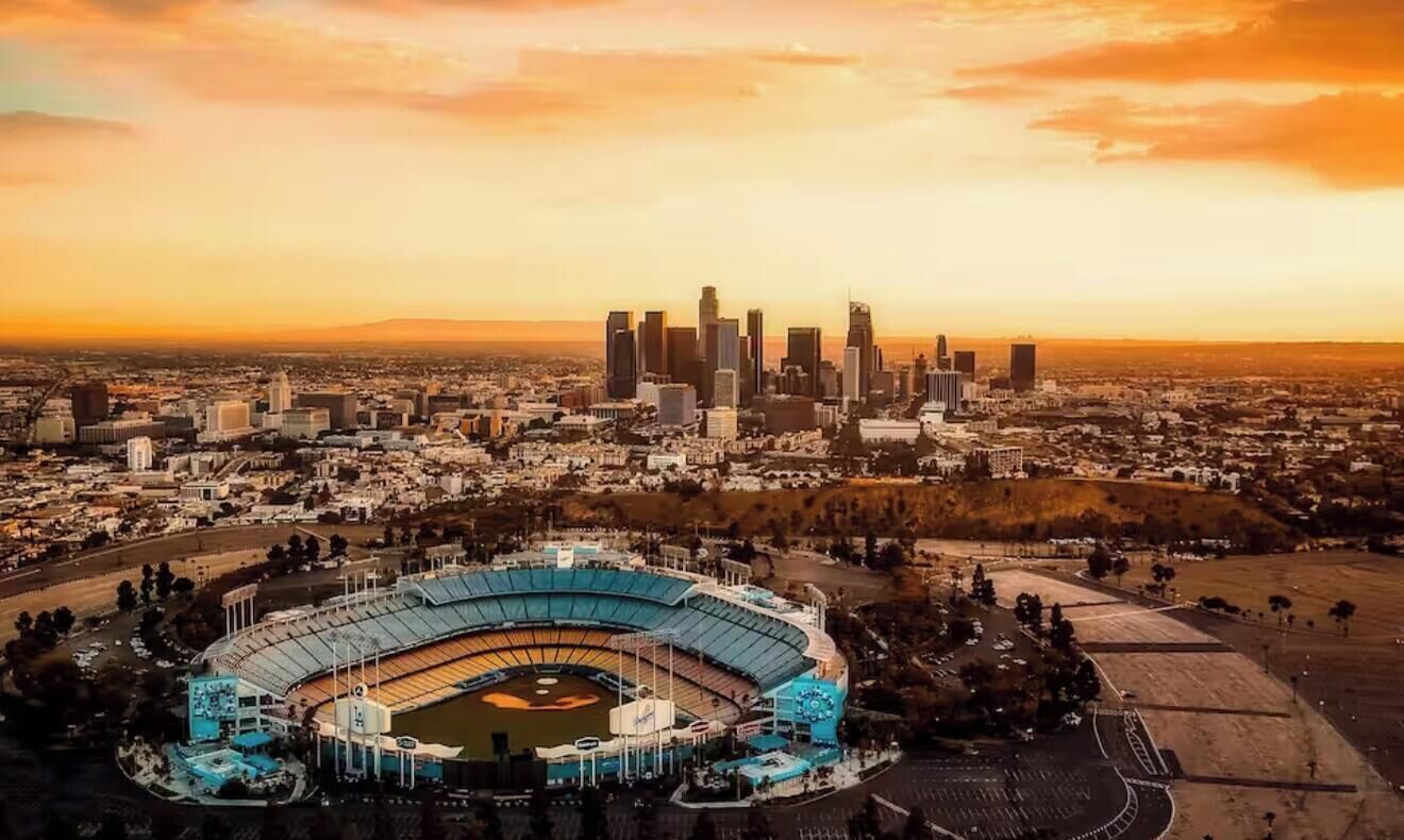 An aerial view of a stadium surrounded by a cityscape during sunset.