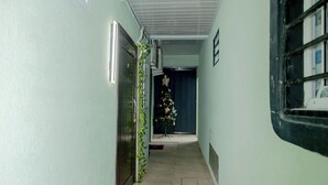 A corridor with light green walls, a tiled floor, and a Christmas tree in the distance.