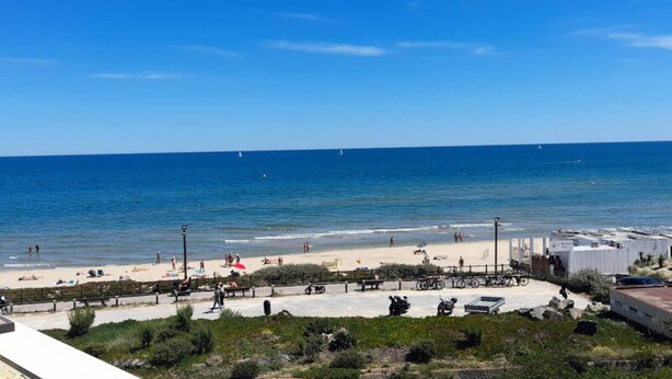 A coastal beach scene with a clear sky, sandy beach, and a few people. - Holiday Home in Heliopolis With Sea View (Agde)
